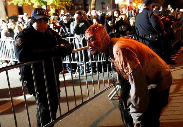 A person in costume waits at a barricade with police officers for the New York City Halloween parade in New York City 
