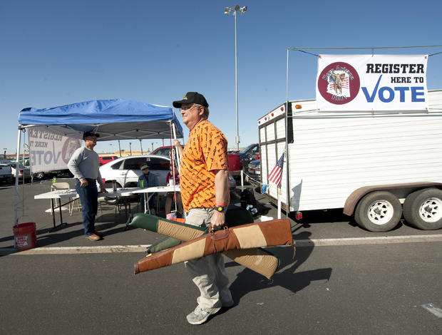 A man carries his guns past a voter regi 