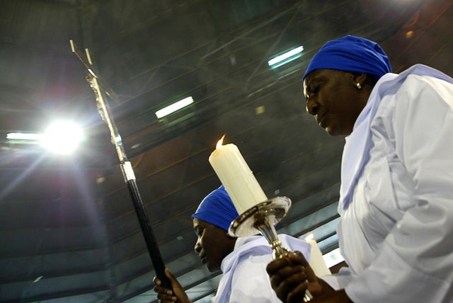 Two women hold a candle and a cross as t 