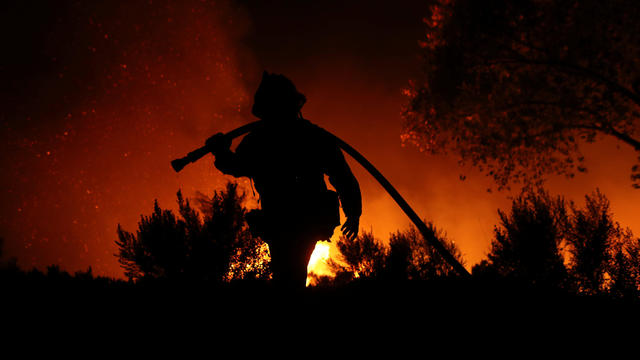 A firefighter works at the top of a hill as the Lilac Fire, a fast moving wild fire, burns through Bonsall, California 