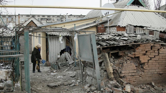 A woman cleans up debris near her house damaged by recent shelling in the rebel-held town of Yasynuvata 