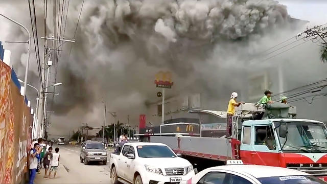 People watch as smoke rises from burning mall's 3rd floor, in Davao City 