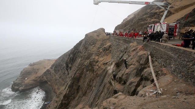 Rescue workers work at the scene after a bus crashed with a truck and careened off a cliff along a sharply curving highway north of Lima 