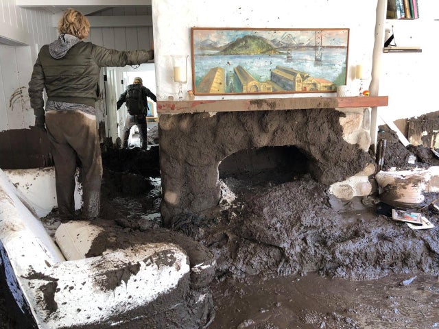 Family members inspect the inside of a home covered in mud following the mudslides in Montecito