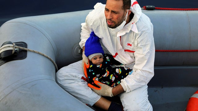 A member of a rescue team carries a migrant baby after being rescued by Libyan coast guards in the Mediterranean Sea off the coast of Libya 