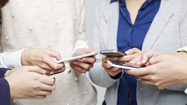 group of young people playing with cellphones together 