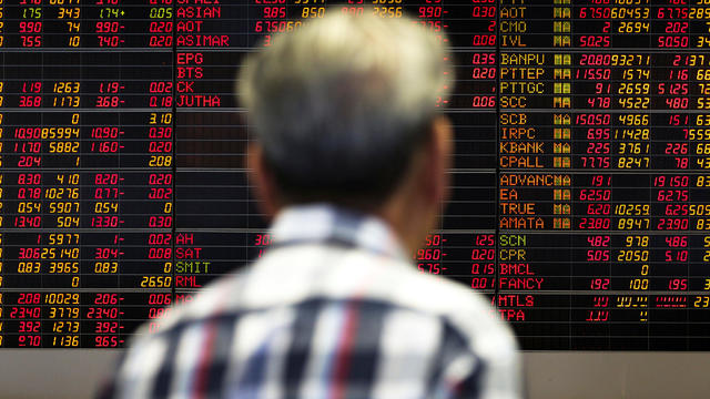 A man monitors a stock index board at a bank in Bangkok 