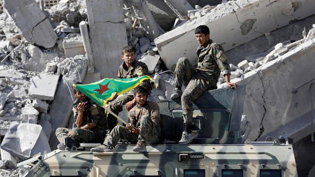 FILE PHOTO: Fighters of Syrian Democratic Forces ride atop an armoured vehicle after Raqqa was liberated from the Islamic State militants, in Raqqa 