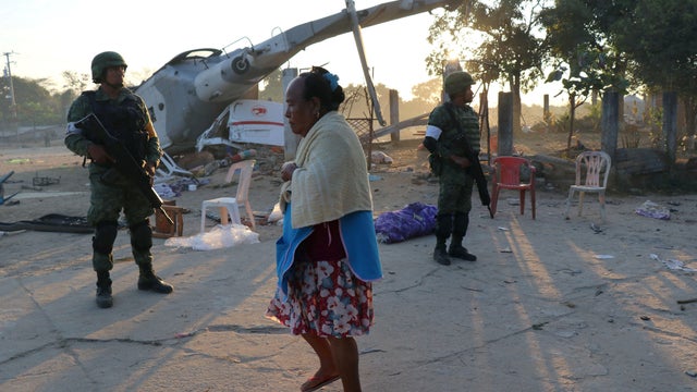 Soldiers stand guard next to a military helicopter, carrying Mexico's interior minister and the governor of the southern state of Oaxaca, crashed on top of two vans in an open field while trying to land in Santiago Jamiltepec 