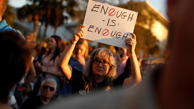 A woman holds a placard during a candlelight vigil for victims of yesterday's shooting at nearby Marjory Stoneman Douglas High School, in Parkland 