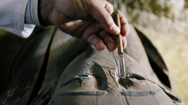 Egyptian antiquities worker brushes a coffin inside the recently discovered burial site in Minya 