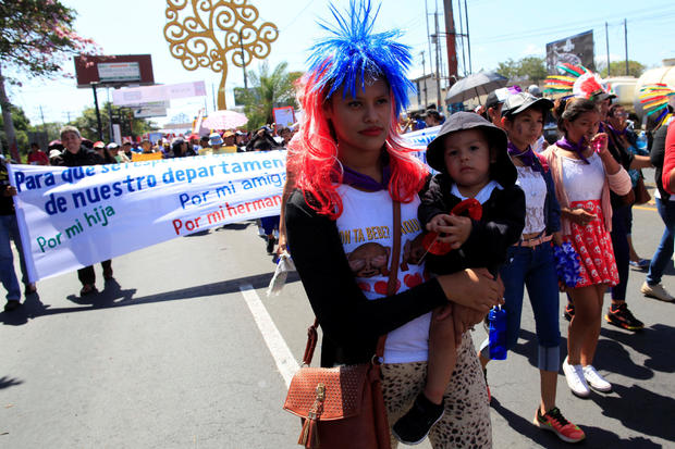 An activist carries her son during a march to mark International Women's Day in Managua 