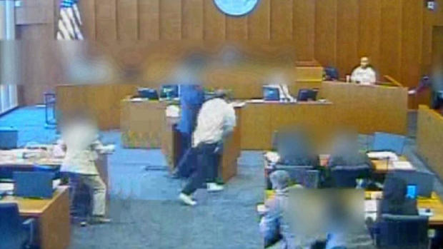 In this image capture from video provided to CBS Salt Lake City affiliate KUTV, Siale Angilau, center, rushes the witness stand in a federal courtroom in 2014. 