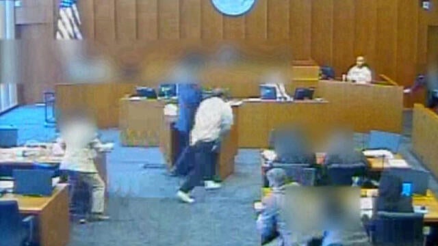 In this image capture from video provided to CBS Salt Lake City affiliate KUTV, Siale Angilau, center, rushes the witness stand in a federal courtroom in 2014.