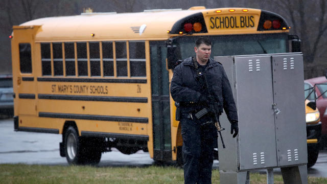 A heavily armed law enforcement officer stands guard as students from Great Mills High School are evacuated to Leonardtown High School following a school shooting at Great Mills High School March 20, 2018, in Great Mills, Maryland. 