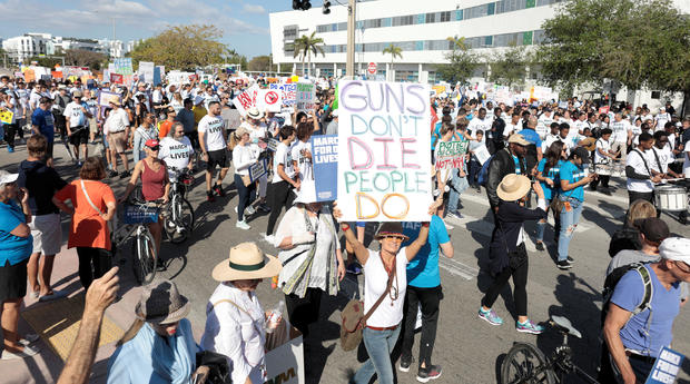 People and students hold signs while rallying in the street during the "March for Our Lives" demanding stricter gun control laws at the Miami Beach Senior High School, in Miami 