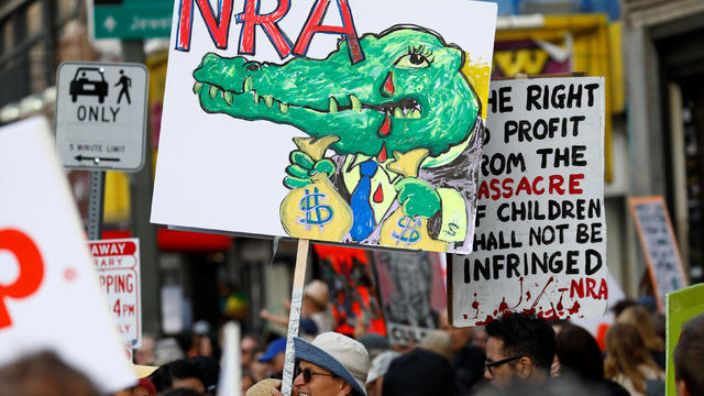 People walk with signs against the NRA during "March for Our Lives", an organized demonstration to end gun violence, in downtown Los Angeles 