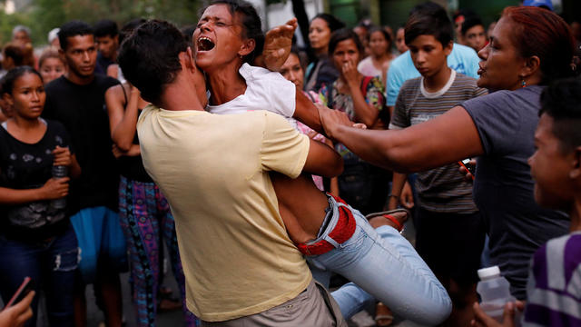 Relatives of inmates held at the General Command of the Carabobo Police react as they wait outside the prison where a fire occurred in the cells area in Valencia 