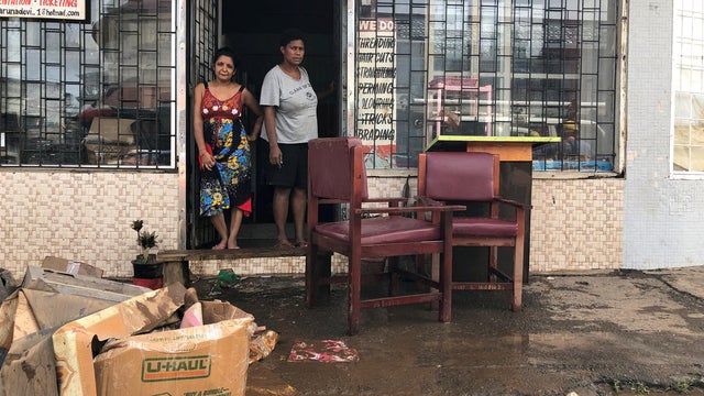 People stand outside business after flooding from Tropical Cyclone Josie in Ba