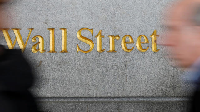 People walk by a Wall Street sign close to the NYSE in New York 