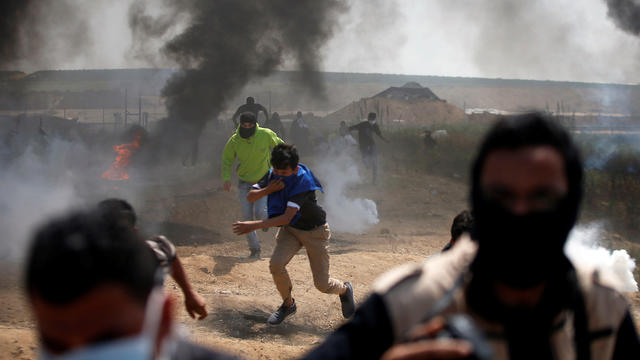 Palestinian demonstrators run during clashes with Israeli troops at the Israel-Gaza border east of Gaza City 