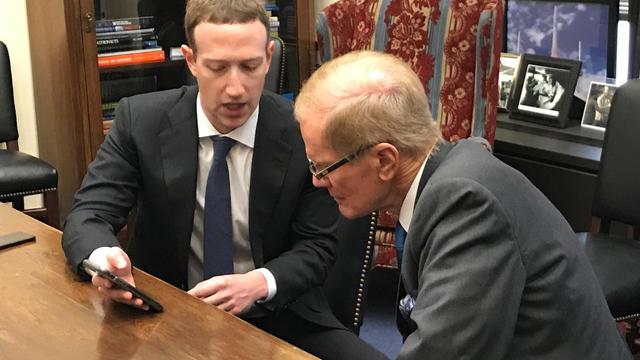 Facebook CEO Mark Zuckerberg holds a mobile phone while speaking with Senator Bill Nelson in Washington 