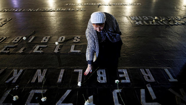 A woman places a flower next to the name of a former death camp as she visits the Hall of Remembrance at the Yad Vashem World Holocaust Remembrance Center, on the annual Israeli Holocaust Remembrance Day, in Jerusalem 