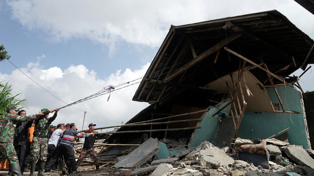 Security personnel and rescue workers pull the remains of a building down following yesterday's 4.4 magnitude quake in Kertosari Village, Banjarnegara, Central Java 
