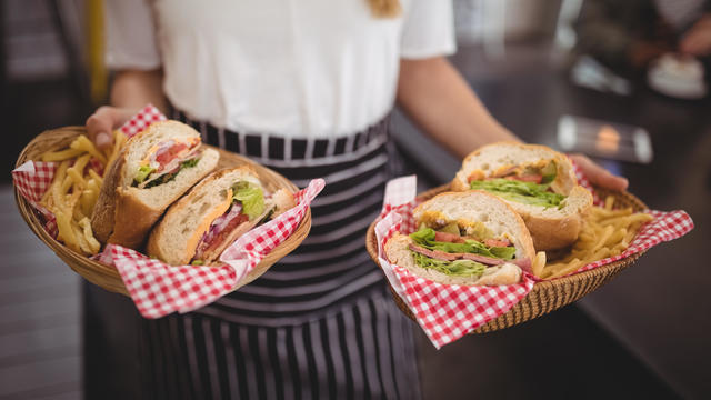 Midsection of waitress holding fresh fast food in wicker baskets 