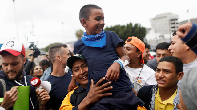 A man and his son, members of a caravan of migrants from Central America, react near the San Ysidro checkpoint as the first fellow migrants entered U.S. territory to seek asylum on Monday, in Tijuana 