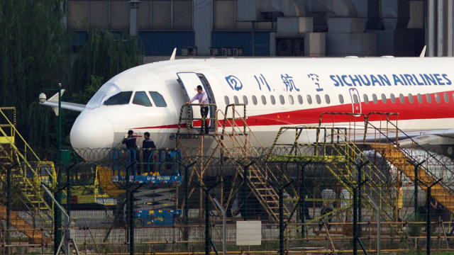 Workers inspect a Sichuan Airlines aircraft that made an emergency landing after a windshield in the cockpit broke off at an airport in Chengdu, China, May 14, 2018. 