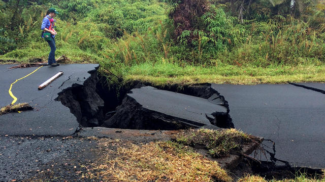 A geologist inspects cracks on a road in Leilani Estates, following eruption of Kilauea volcano, Hawaii 