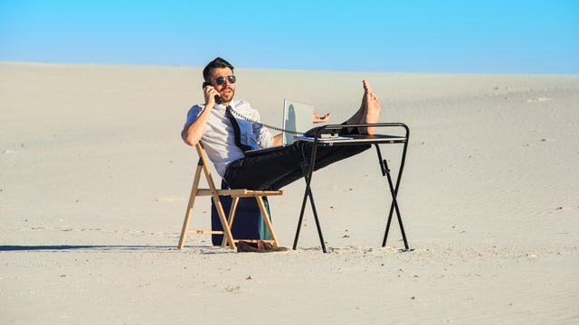 Businessman using  laptop in a desert 