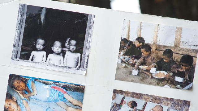 A woman holds up a poster with photos fr 