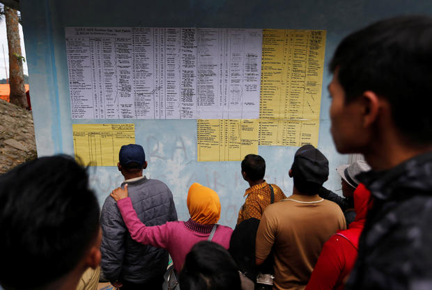 Villagers and relatives look at a list of missing passengers from Monday's ferry accident at Lake Toba in Simalungun 