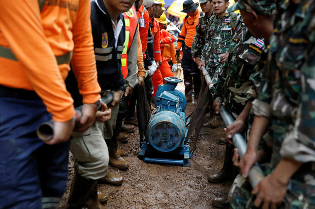 Soldiers and rescue workers carry a water pump to the Tham Luang cave complex during a search for members of an under-16 soccer team and their coach, in the northern province of Chiang Rai 