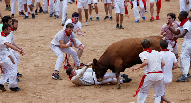 A reveller is tossed by a wild cow following the first running of the bulls at the San Fermin festival in Pamplona 