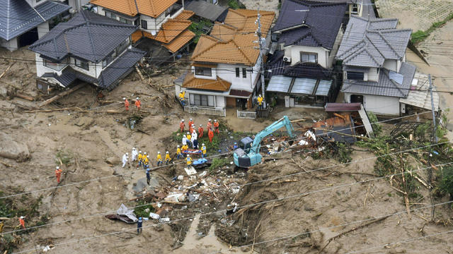 Rescue workers are seen next to houses damaged by a landslide following heavy rain in Hiroshima 