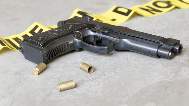 Crime scene concept with gun and three casings - handgun, police tape, generic 