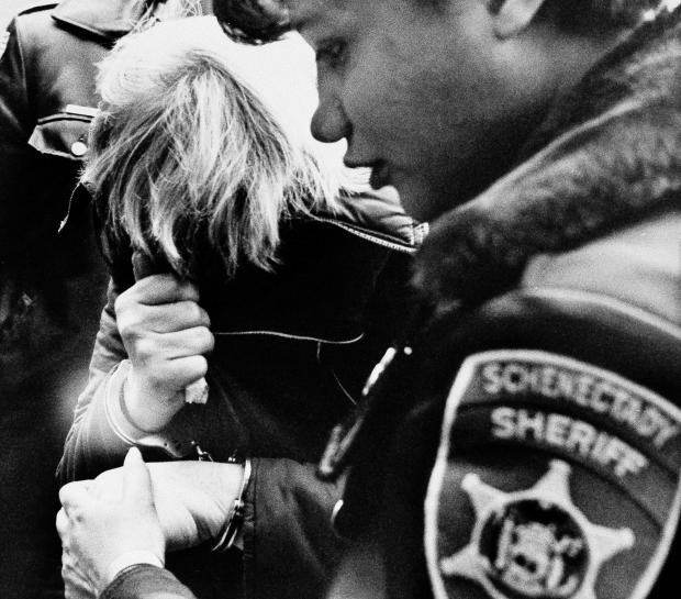 Marybeth Tinning, suspected by Schenectady police of killing the nine children in her care since 1972, covers her face while being escorted by a Schenectady County sheriff's deputy to court for a preliminary hearing on Feb. 11, 1986. 