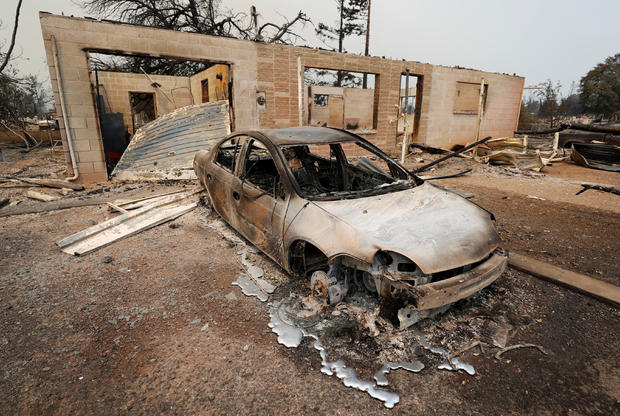 A scorched car sits next to a home that burned in the Carr Fire west of Redding 
