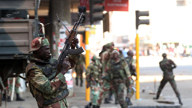 Members of the military gesture to the photographer as they patrol the streets of the capital Harare 