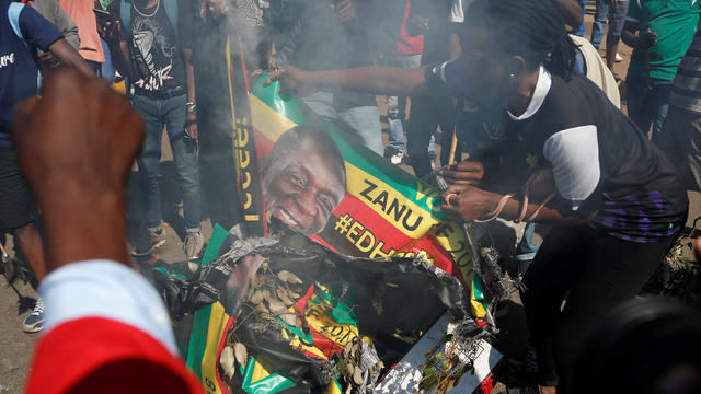 Supporters of the opposition Movement for Democratic Change party (MDC) of Nelson Chamisa burn an election banner with the face of Zimbabwe's President Emmerson Mnangagwa in Harare 