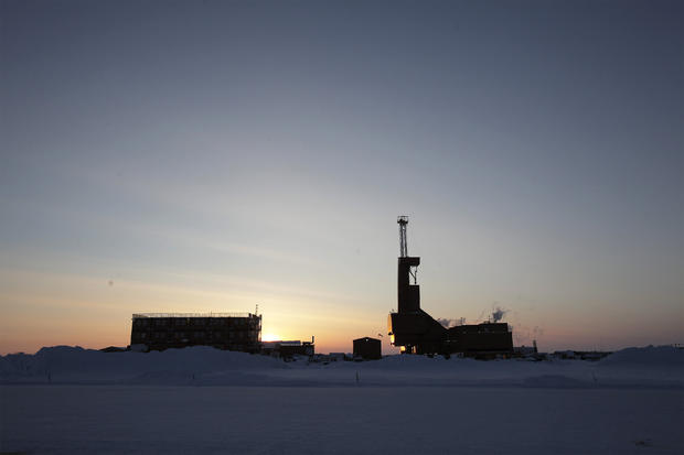 The sun sets behind an oil drilling rig in Prudhoe Bay, Alaska 