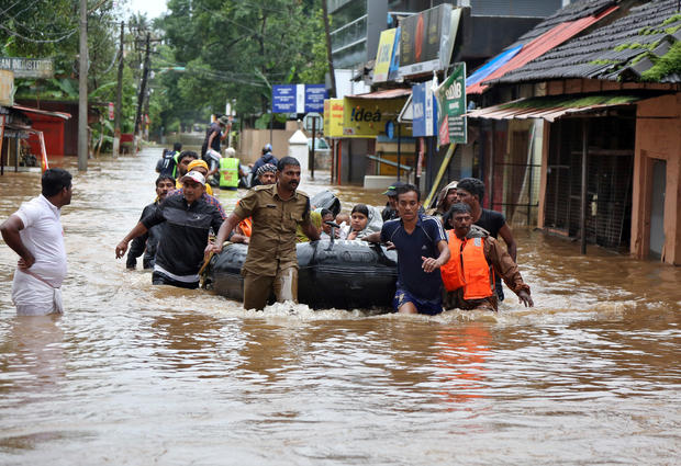 Rescuers evacuate people from a flooded area to a safer place in Aluva 
