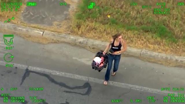 woman-runs-from-cops-with-baby-carrier.jpg 