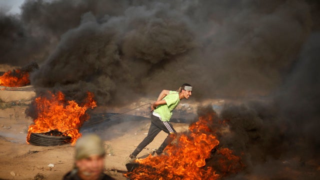 Palestinian demonstrator pulls a burning tyre during a protest at the Israel-Gaza border fence east of Gaza City 
