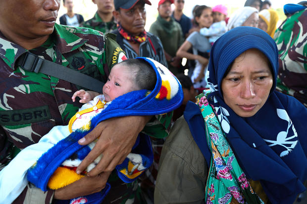 A soldier holds a infant while standing next to his mother as they are affected by earthquake and tsunami and wait for a military aircraft at Mutiara Sis Al Jufri Airport in Palu, Central Sulawesi 