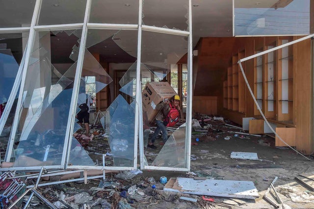 A man carries a box from a shopping mall following an earthquake and tsunami in Palu, Central Sulawesi 