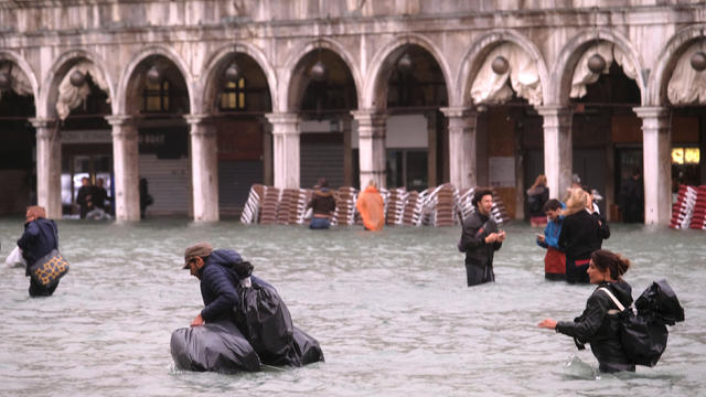 People walk in a flooded Saint Mark Square during a period of seasonal high water in Venice 